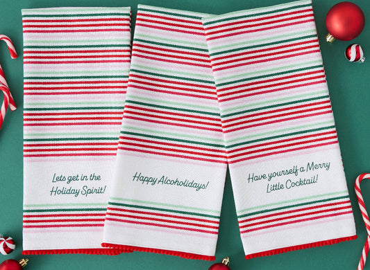 Three striped towels with humorous holiday sayings on a green background.