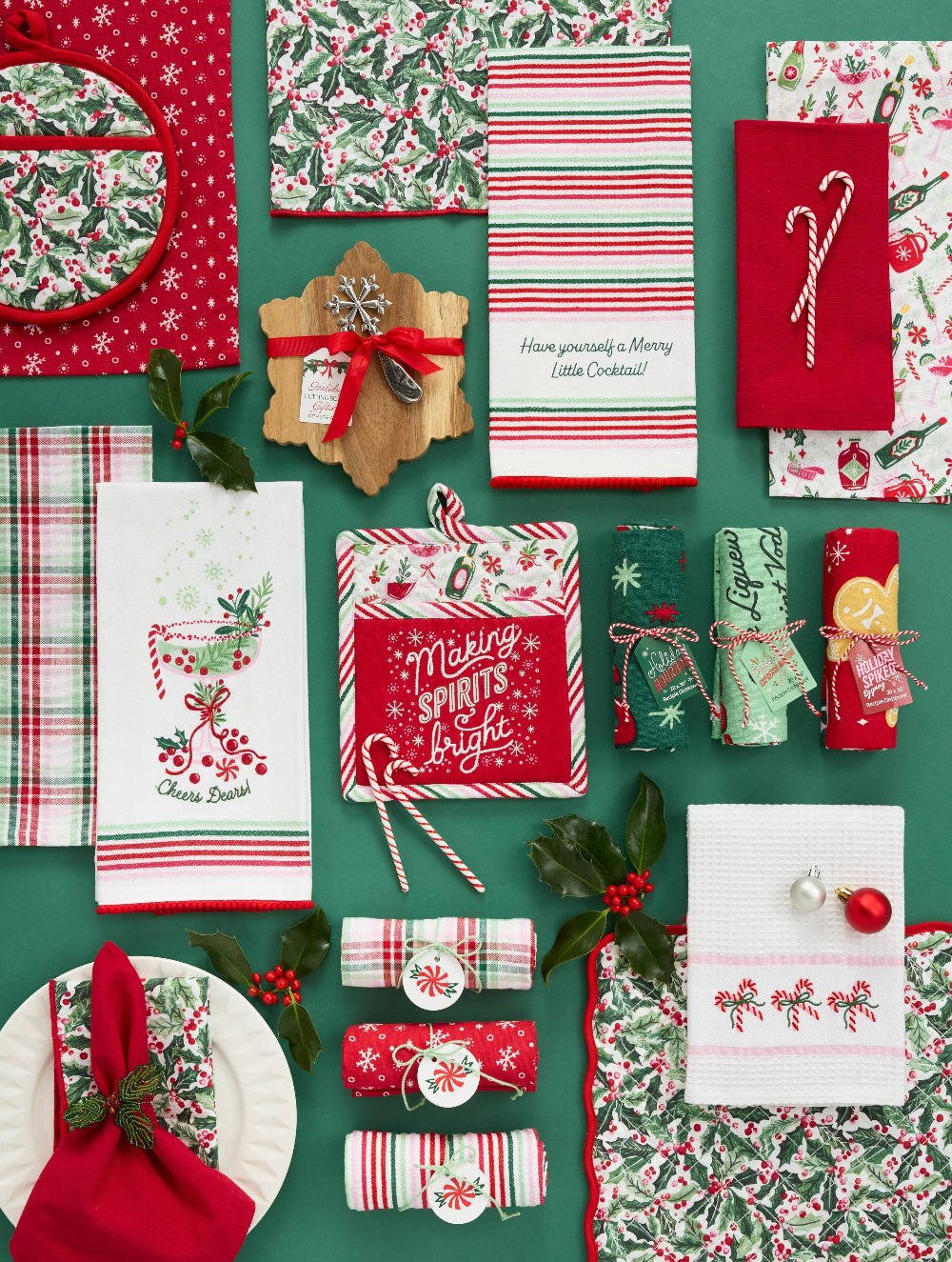 Collection of Christmas-themed kitchen items including towels, napkins, and cutlery on a green background.